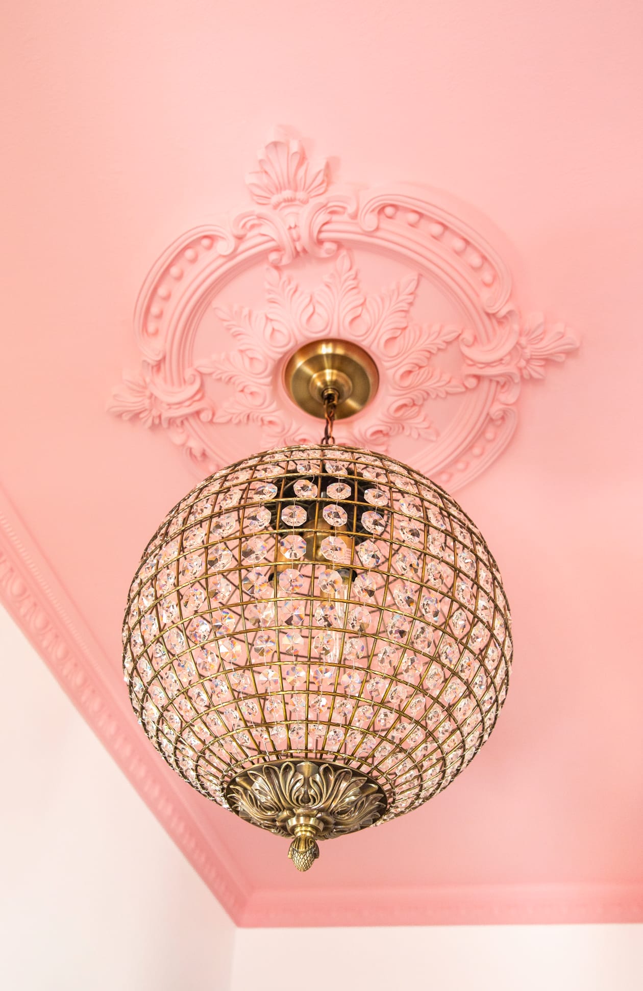 Pink crown moulding with chandelier in a colorful entryway